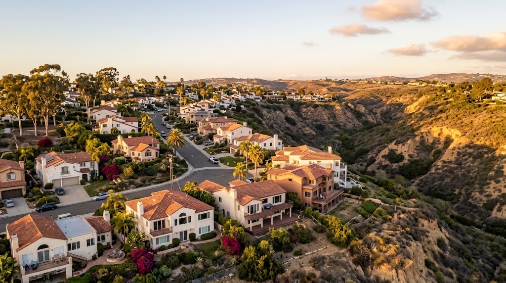 A San Diego hillside neighborhood at golden hour, with stucco homes and a canyon or open space edge behind them