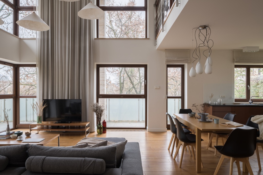 Modern Double Height Living and Dining Area with Loft Overhang Floor to Ceiling Windows and Oak Floors.jpg