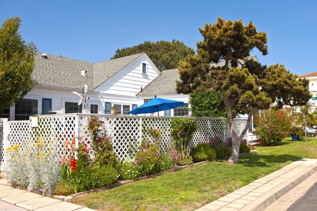 Pacific Beach Coastal Cottage with White Lattice Fence Blue Umbrella and Lush Garden.jpg
