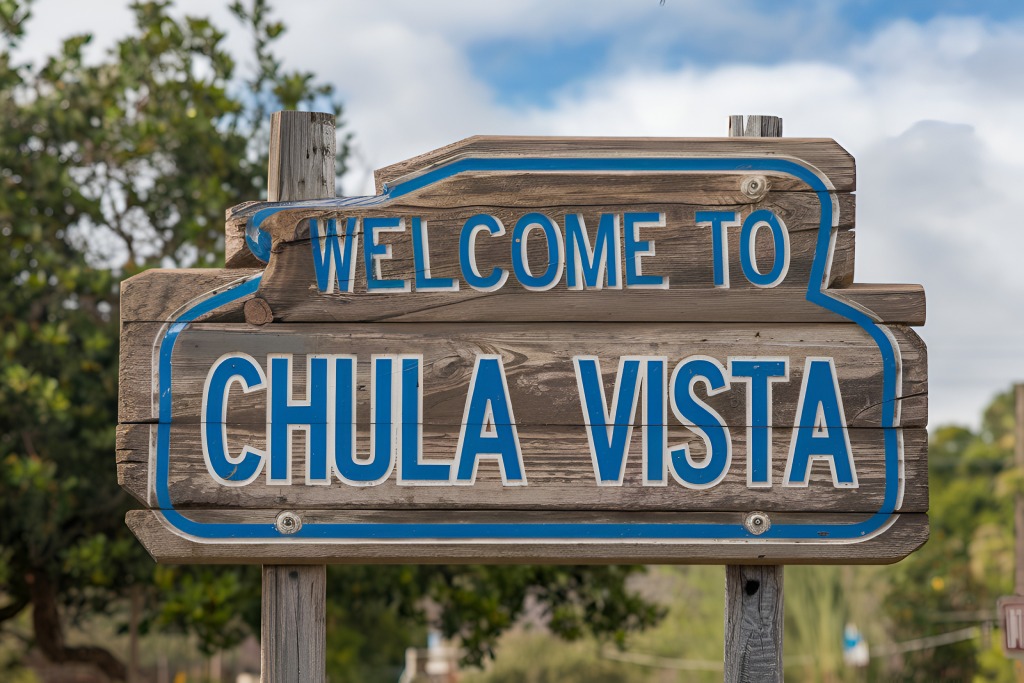 Welcome to Chula Vista Rustic Wooden Sign with Blue Lettering and Blurred Natural Background.jpg